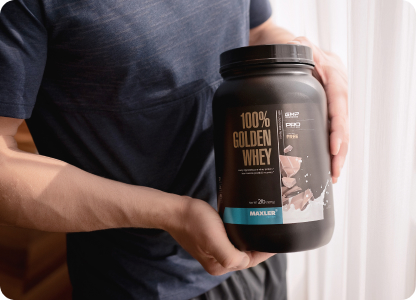A photo of a man holding a 100% Golden Whey container.