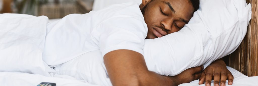 A man sleeping on white bedsheets