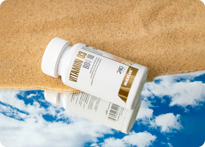 A vitamin D bottle laying on sand