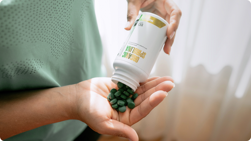 Person pouring Maxler Organic Spirulina tablets into their hand, emphasizing daily nutrition and natural wellness benefits